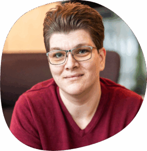 Alexis trägt eine Brille, kurze Haare und ein rotes Shirt