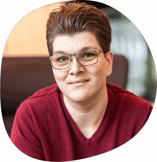 Alexis trägt eine Brille, kurze Haare und ein rotes Shirt