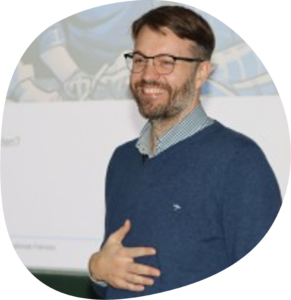 Dr. Sebastian Tillmann trägt eine Brille, ein kariertes Hemd und einen blauen Pullover.