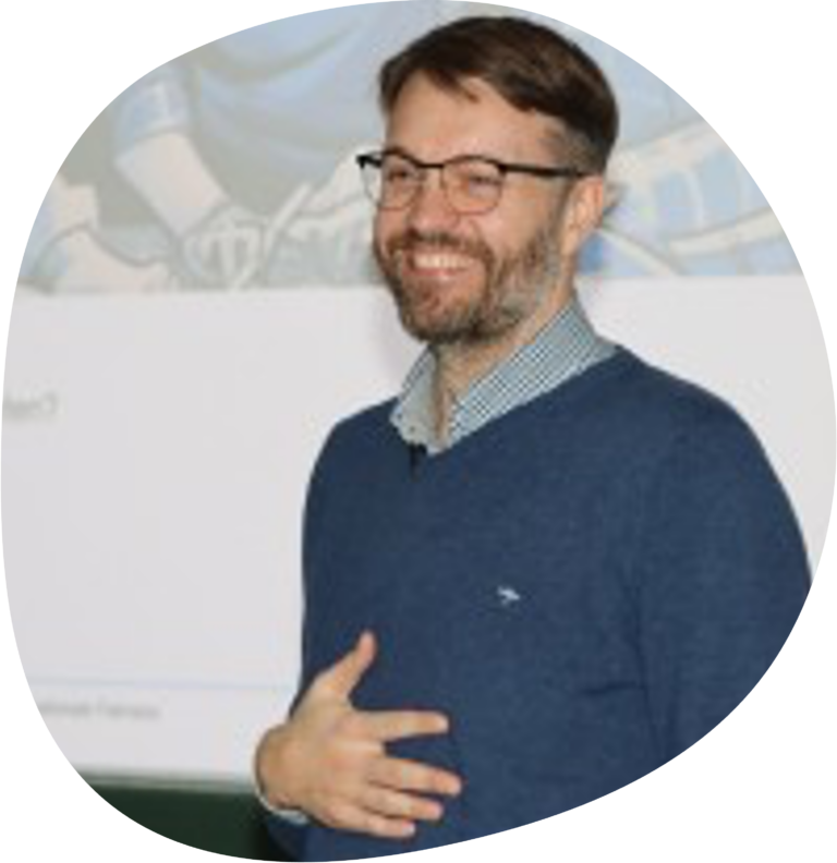 Dr. Sebastian Tillmann trägt eine Brille, ein kariertes Hemd und einen blauen Pullover.