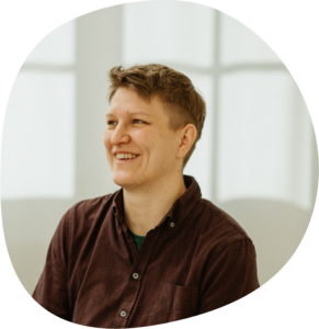 Sophia trägt kurze braune Haare mit einem Undercut und ein braunes Hemd