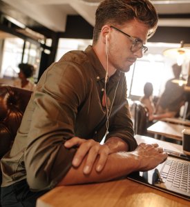 Mann mit Kopfhörern arbeitet konzentriert am Laptop