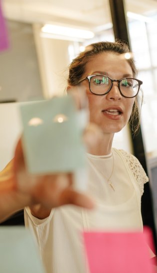 Frau klebt Notizzettel an eine Glaswand